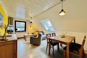 Ein stilvolles Loft-Zimmer mit Essbereich, einer Couch und einem Fenster mit Blick auf die Stadt.