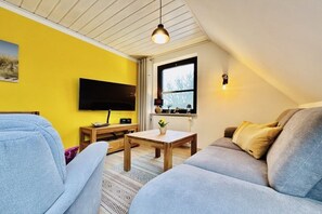Ein Wohnzimmer mit einer Couch, einem Couchtisch, einem Flachbildfernseher und einem Fenster mit Blick.