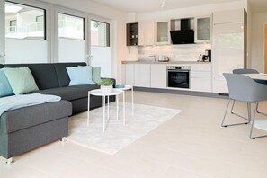A modern living space with a sofa, a small round table, and a dining area with chairs. - House on the beach, Apartment 1 (Scharbeutz)