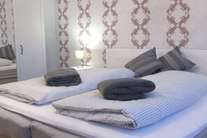 Une chambre d’hôtel avec deux lits, chacun recouvert d’une courtepointe à carreaux et agrémenté d’oreillers, une table de chevet avec une lampe et une armoire.