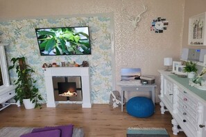 Ein Wohnzimmer mit Kamin, einem darüber hängenden Fernseher und einem blauen Fitnessball.