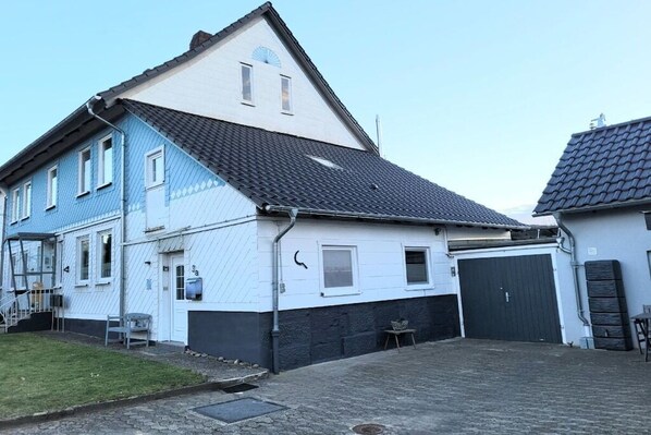 En tvåvåningsbyggnad med ett garage och en liten utesittplats.