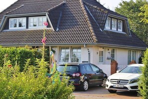 Ein zweistöckiges Haus mit Satteldach, einer Garage und zwei geparkten Autos davor.