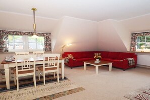 Ein Wohnzimmer mit einem roten Sofa, einem Esstisch mit Stühlen und einem Couchtisch.