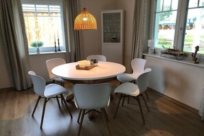 Un tavolo rotondo da pranzo con sei sedie, un lampadario e una finestra con tende.