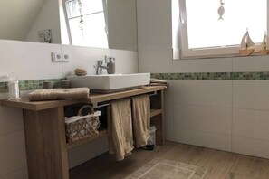 Un bagno con un mobile contenitore in legno, un lavandino bianco e una finestra vista.