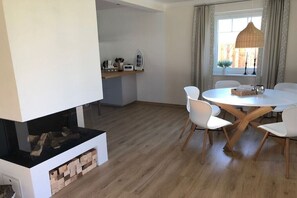 A modern kitchen with a dining area, wooden flooring, and a large window with curtains. - Holiday home with 1 bedroom (Rheinsberg OT Flecken Zechlin)