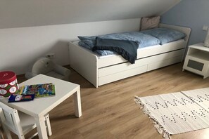 Una camera da letto piccola e ordinata con un letto singolo, una scrivania bianca e un tavolino.