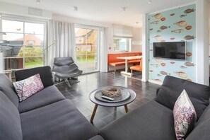 Ein modernes Wohnzimmer mit einer Couch, einem Couchtisch und einem an der Wand befestigten Fernseher.