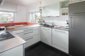Eine moderne Küche mit weißen Schränken, einem schwarzen Fliesenboden und einem eingebauten Backofen.