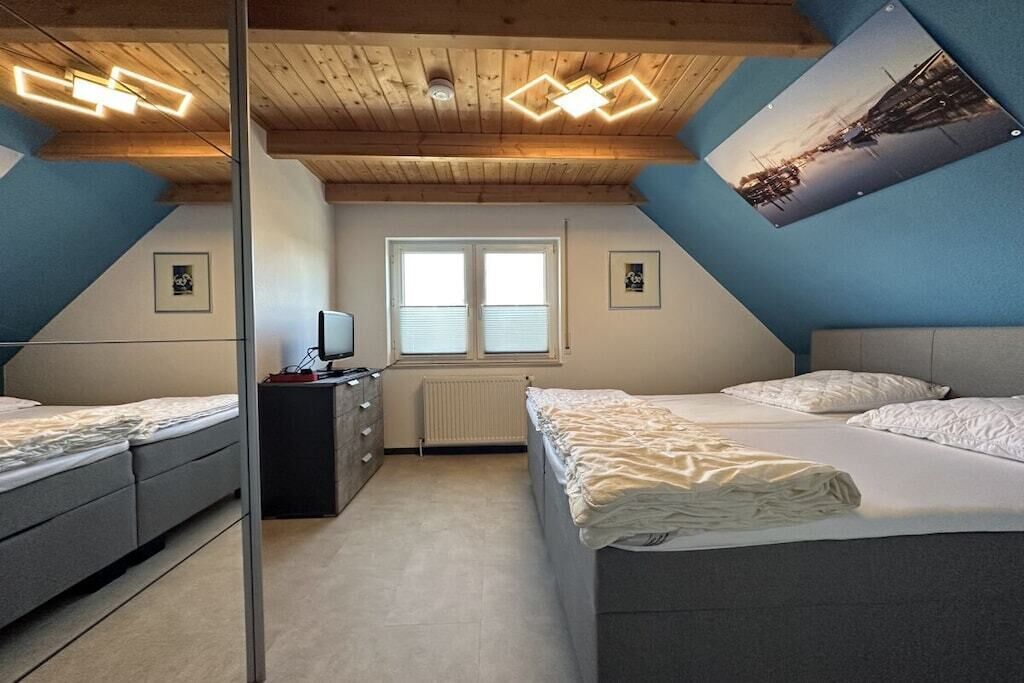 Ein Schlafzimmer mit zwei Betten, einem Fenster, einer Heizung und einem Bild an der Wand.
