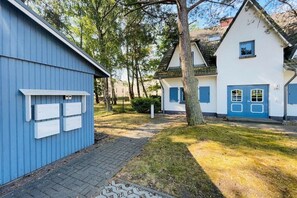 A residential area with a blue building, a white house with blue shutters, and a paved pathway. - Holiday apartment with 1 bedroom (Dierhagen)