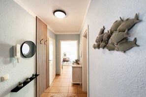 A hallway with a wooden door, a round mirror, and a wall-mounted fish decoration. - Holiday apartment with 1 bedroom (Dierhagen)