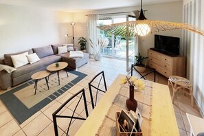A modern living room with a sofa, coffee table, dining table, and TV. - Holiday apartment with 1 bedroom (Dierhagen)