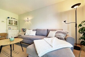 Ein Wohnzimmer mit einer Couch, einem Couchtisch, einer Lampe, einem Schrank und einer Pflanze.