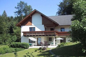 A two-story house with a balcony, a covered patio with outdoor furniture, and a well-maintained garden. - 1 Buchenheim House Rena (Reifnitz)