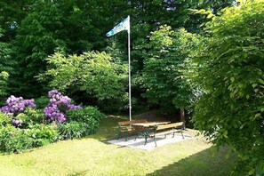 A park with a flagpole, benches, and lush greenery. - 1 Buchenheim House Rena (Reifnitz)