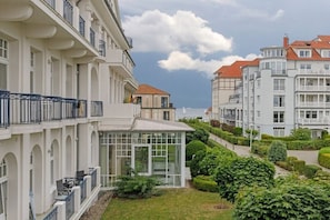 A multi-story residential building with balconies, a conservatory, and a well-maintained garden. - Holiday apartment Haus am Park 322251 (Kühlungsborn)
