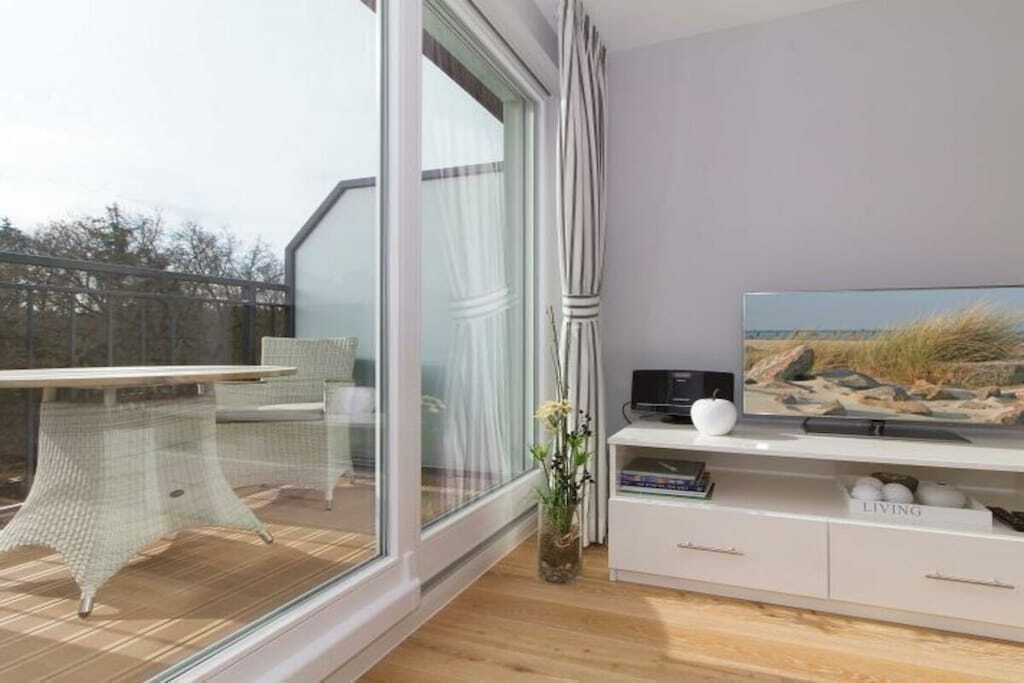 Ein modernes Wohnzimmer mit einem großen Fenster, einem Flachbildfernseher und einer weißen Unterhaltungsanlage.