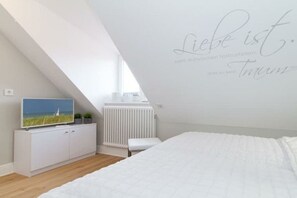 Ein Schlafzimmer mit einem Bett, einem weißen Schrank mit Fernseher und einer Wand mit einer Beschriftung.