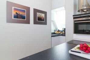 A modern kitchen with a black countertop, stainless steel appliances, and two framed pictures on the wall. - Holiday apartment Villa Löwenstein 319571 (Kühlungsborn)