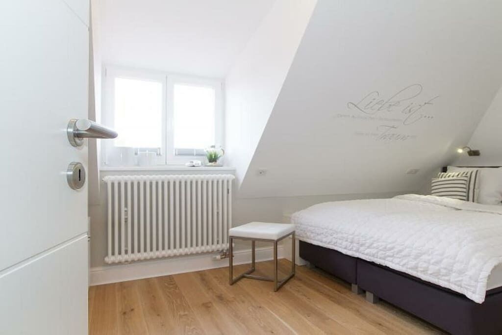 Un dormitorio con cama, radiador, ventana y puerta.