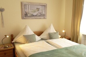 A bedroom with a bed, pillows, a nightstand, a lamp, a wall-mounted picture, and a curtain. - 2 Decker Elms Volcanic Eifel (Ulmen)