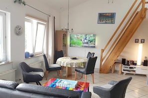 A living room with a sofa, chairs, a table, a TV, and a staircase. - Baltic Sea view - beach only 190m (Karlshagen)