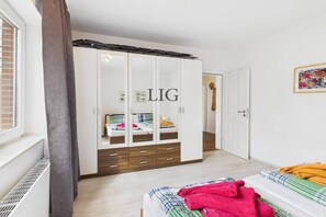 A bedroom with a wardrobe, a bed, and a window. - Holiday apartment Strandhaus 7 (Langeoog)