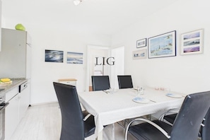 A modern dining area with a white table, black chairs, and framed artwork on the walls. - Holiday apartment Strandhaus 7 (Langeoog)