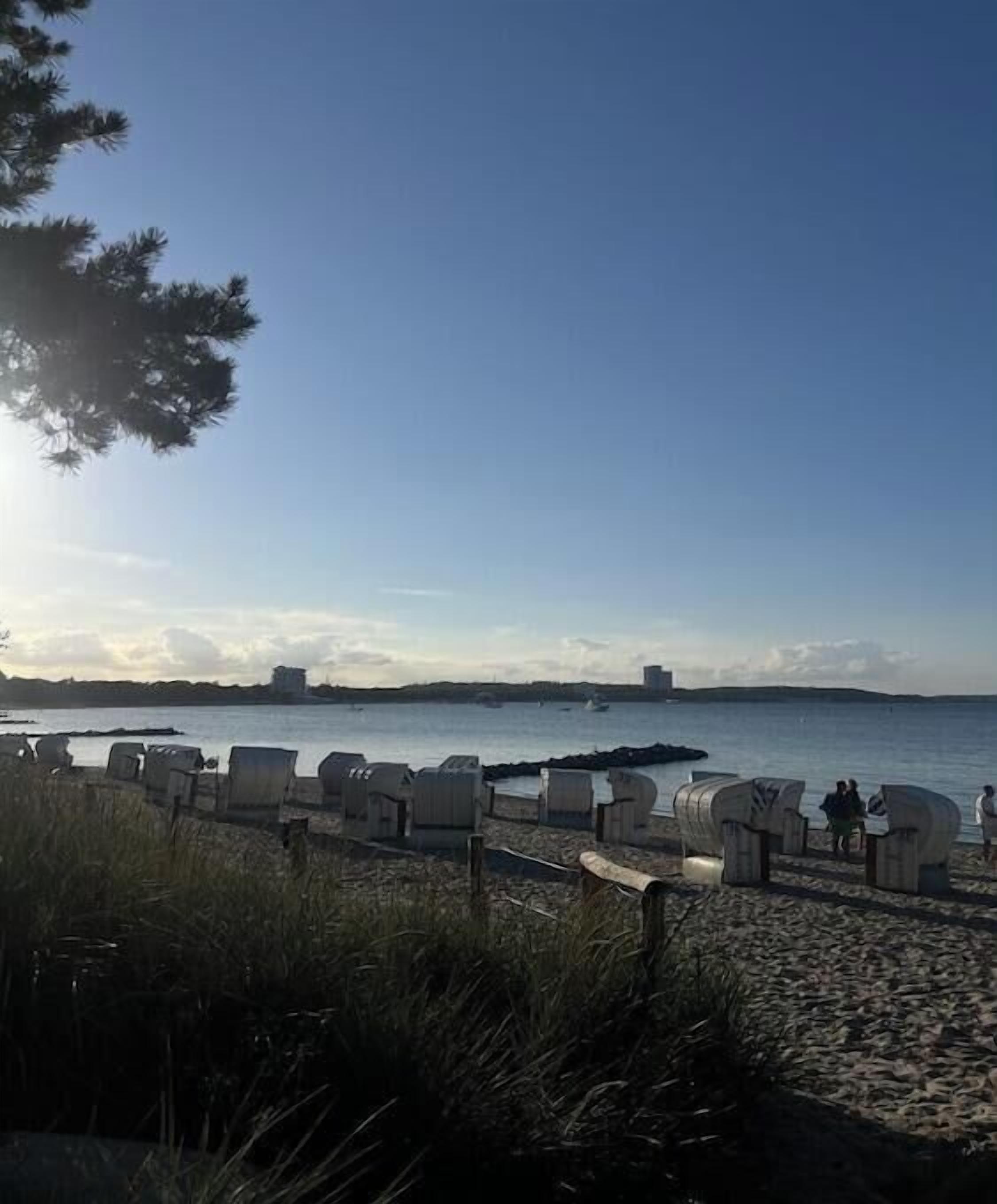 Ein Strand mit einer Reihe Strandkörben und einer entfernten Wassersicht.