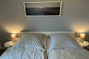 Un letto matrimoniale con due comodini, ognuno dotato di una lampada, in una stanza con un quadro appeso al muro.