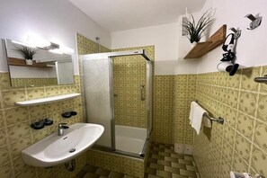 Un bagno con doccia, lavandino e specchio.