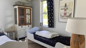 A bedroom with a single bed, a wooden cabinet with glass doors, a window with star-patterned curtains, and a framed picture of a lighthouse. - Friesche Zusje Holiday Home with Terrace, Garden, Jetty & Wi-Fi in Makkum (Makkum)