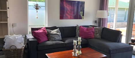 A living room with a grey sofa, a wooden coffee table, and a painting on the wall.