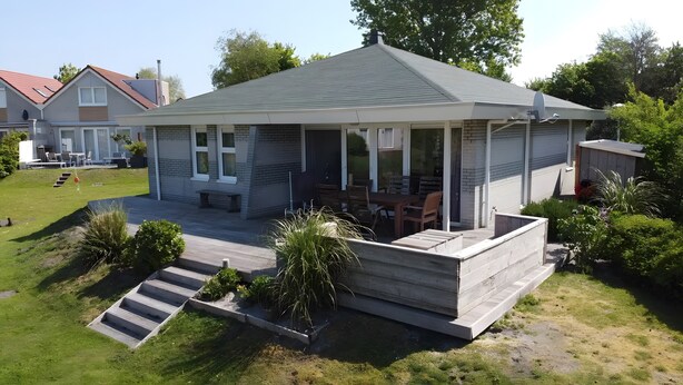 A house with a covered patio, a small deck, and a grassy yard. - Friesche Zusje Holiday Home with Terrace, Garden, Jetty & Wi-Fi in Makkum (Makkum)
