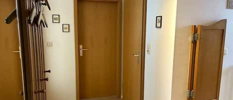 A hallway with wooden doors, a coat rack, and a wall-mounted cabinet.