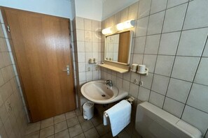 A bathroom with a wooden door, a sink, a mirror, and a bathtub. - Holiday apartment in Büsum with swimming pool (Büsum)