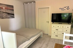 A bedroom with a bed, a television, a dresser, and a door with a heart decoration. - Holiday apartment in Büsum with swimming pool (Büsum)