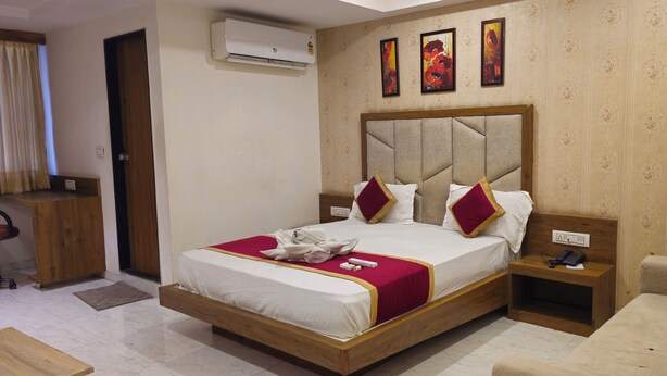 Una habitación de hotel con una cama, mesita de noche y un banco de madera.