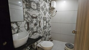 Un baño con pared de mármol, un lavabo, un inodoro y una ducha.