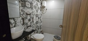A bathroom with a marble wall, a sink, a toilet, and a shower. - Hotel Lee Grand Inn (Ahmedabad)