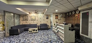 A reception area with a check-in counter, two sofas, and a patterned floor. - Hotel Lee Grand Inn (Ahmedabad)