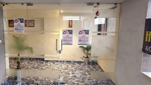 Zona de recepción de hotel con un separador de vidrio, piso de mármol y varios carteles publicitarios del hotel.
