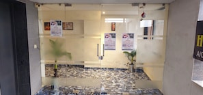 Zona de recepción de hotel con un separador de vidrio, piso de mármol y varios carteles publicitarios del hotel.