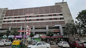 Un edificio de varios pisos con letreros que indican Hotel Shreeji, un restaurante y un banco.
