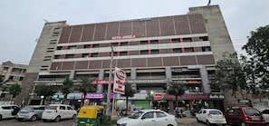 Un edificio de varios pisos con letreros que indican Hotel Shreeji, un restaurante y un banco.
