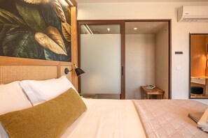 A hotel room with a bed, a nightstand, a wall-mounted lamp, a sliding door, and a small table with a chair. - Sia Elafonisi Pool House (Chrysoskalitissa, Kreta)