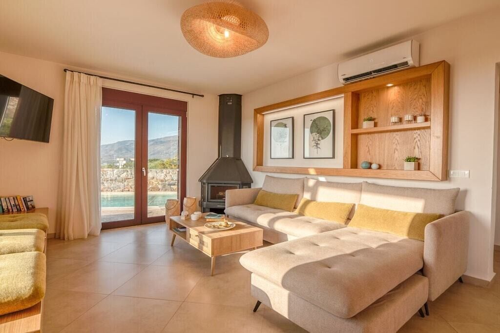 Un salon moderne avec une cheminée, un canapé, une table basse et une vue sur l’extérieur.