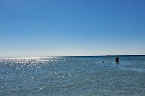 A clear blue sky over a calm sea with a person standing in the water. - Sia Elafonisi Pool House (Chrysoskalitissa, Kreta)